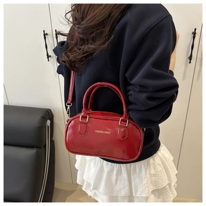 Detail of red glossy leather bowling bag with gold hardware and shoulder strap