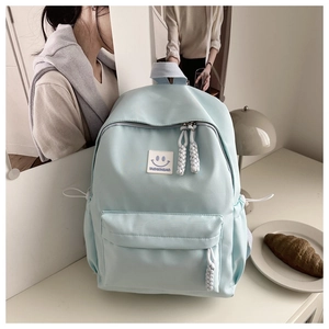 Detail of mint green school backpack with fashion smile label and white braided pullers