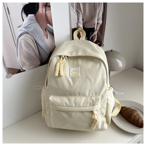 Detail of off-white minimalist canvas backpack with a yellow smiley face patch embroidery