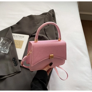 Détail du sac bandoulière rose avec rabat tissé et accents de quincaillerie dorée