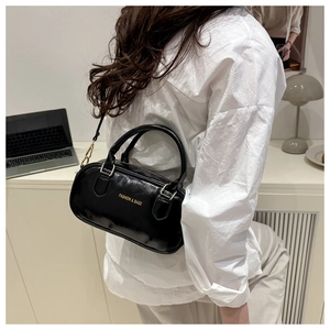 Detail of high-gloss black Boston bag with gold lettering shown on a white shirt