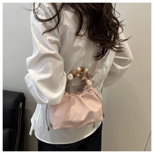 Detail of pink drawstring bucket bag featuring marble bead handle and adjustable strap