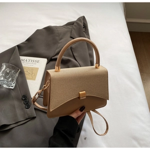 Détail du sac bandoulière carré avec rabat tissé et fermoir métallique doré chic