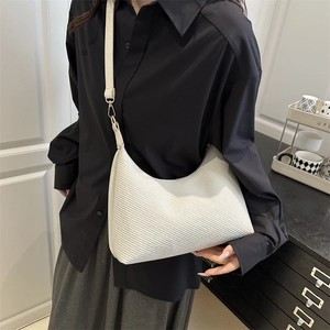 White diagonal textured hobo bag with a minimalist crescent shape and slim shoulder strap