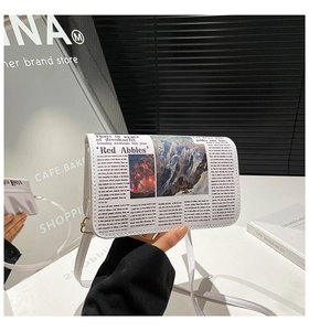 Vue détaillée d'un sac bandoulière blanc enveloppe avec imprimé journal et boucle dorée