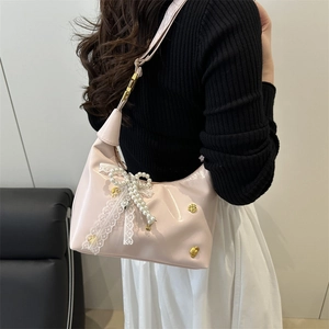 Sac hobo rose avec nœud en dentelle et chaîne de perles porté par un mannequin