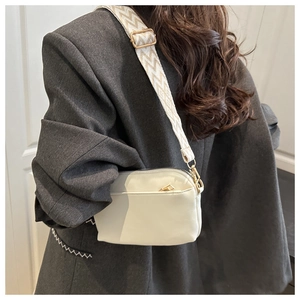 Model wearing a beige crossbody bag with geometric jacquard wide strap on a grey blazer