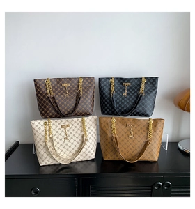 Dettaglio di quattro borse shopping monogrammate in marrone, bianco e nero su un mobile