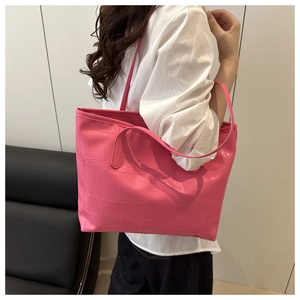 Detail of rose pink tote bag with crocodile pattern texture and leather stitching