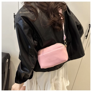 Detail view of pink crossbody square bag showing soft leather texture and metal zipper