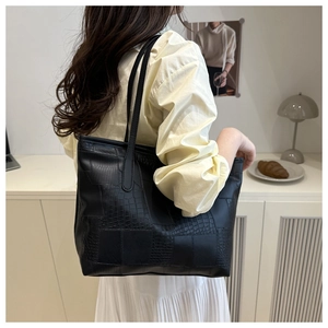 Detail view of black PU leather tote bag with crocodile texture and minimalist straps