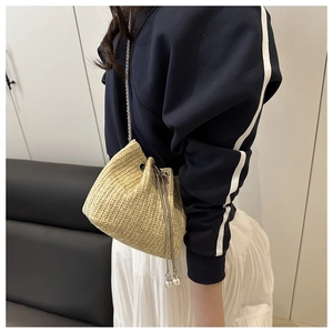 Detail of woven straw bucket bag with silver chain strap and drawstring closure