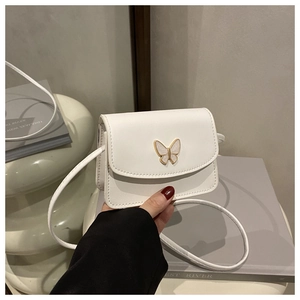 Detail of a white square crossbody bag featuring a golden butterfly clasp and smooth texture