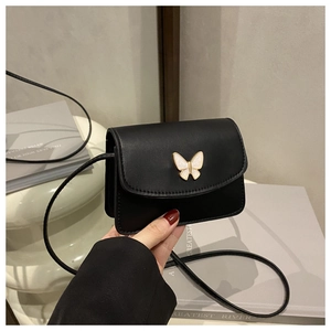 Detail of black square crossbody bag featuring a pearlescent white butterfly buckle