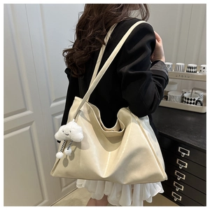 Close-up of cream leather tote bag with lychee texture and fluffy cloud charm on model