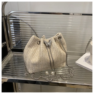 Detailed close-up of woven bucket bag featuring metal butterfly clasp and pearl drawstring