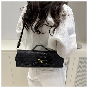 Detailed view of black crocodile pattern baguette bag with gold metal twist buckle on model