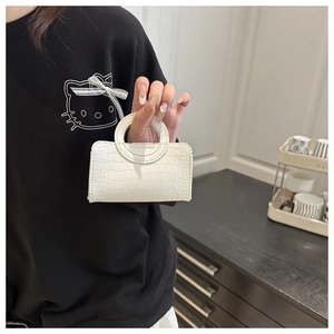 Close-up of white mini crocodile pattern handbag held by hand for scale and texture