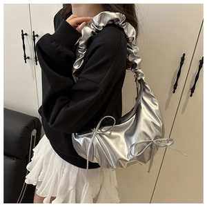 Detail of silver metallic pleated shoulder bag with oversized ruffles and bow accents