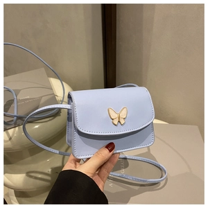 Detail of light blue crossbody bag featuring a golden butterfly clasp and smooth texture