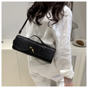 Détail du sac baguette noir à motif crocodile avec son fermoir rotatif en métal doré