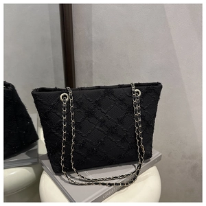 Close-up of black plaid woven tote bag with shimmering sequins and gold chain strap