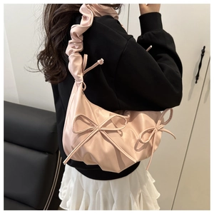 Close-up of pink pleated shoulder bag featuring decorative bows and ruched strap details