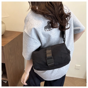 Close-up of black Oxford cloth crossbody bag featuring a durable plastic buckle closure