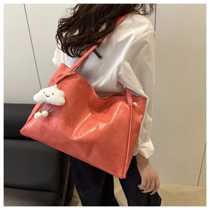 Detail of coral pink tote bag with soft leather texture and white cloud charm