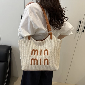 Chic beige straw tote bag with brown leather straps and embroidery shown on model