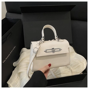 Détail du sac carré blanc cassé avec fermoir chaîne argenté dans une boîte cadeau