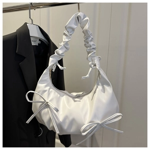 Detailed view of white pleated crescent bag with elegant side bows and ruched handle detail