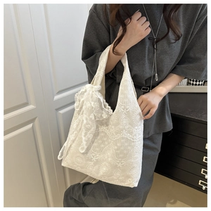 Detailed view of white lace shoulder bag with vintage floral textures and side bow ornament
