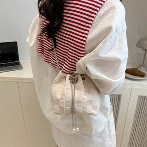 Fashionable beige woven straw bucket bag with pearl drawstring and metal chain strap