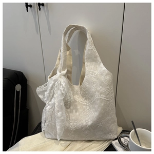 Close-up of white lace floral embroidery and large bow detail on a spacious tote bag