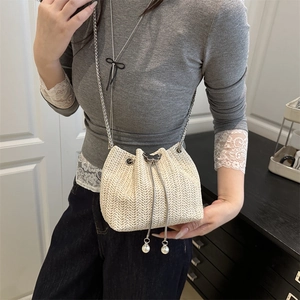 Straw woven bucket bag with pearl tassels and butterfly buckle shown on model