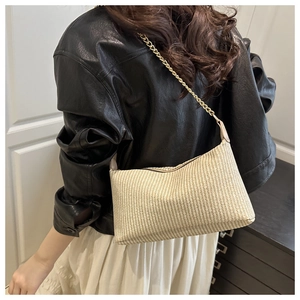 Detail of beige woven pillow bag with gold chain strap on a stylish outfit
