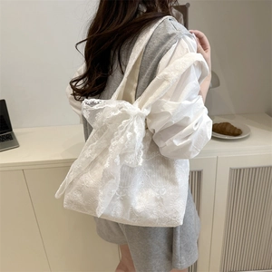 White floral lace tote bag with oversized bows in a modern lifestyle setting