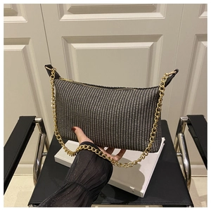 Gros plan du sac bandoulière tissé noir et blanc avec bandoulière chaîne dorée