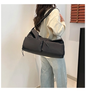 Rear view of a model wearing a black large-capacity canvas messenger bag with pocket details