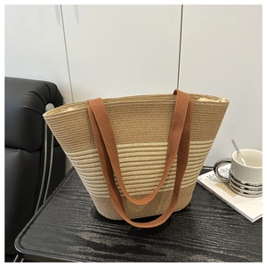 Detail of handwoven tote bag in khaki and brown contrast on a wooden surface