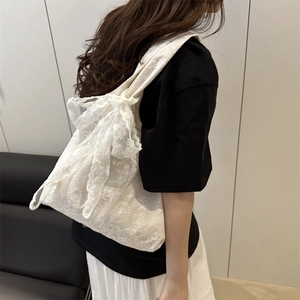 White crochet floral lace tote bag with large bow detail shown on model shoulder