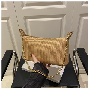 Détail du sac sous le bras en paille beige avec chaîne dorée et fermeture éclair