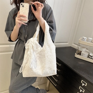 White lace tote bag with floral embroidery and a large decorative bow on the side
