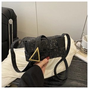 Close-up of black woven leather flap bag with iconic golden triangle buckle and textures