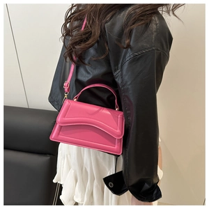 Detail of magenta crossbody bag with wavy texture on a leather jacket backdrop
