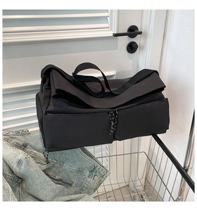 Detail showing high-capacity black nylon messenger bag with double front pockets and wide strap