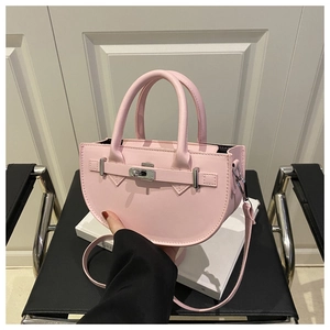 Detailed view of pink leather saddle bag featuring a silver twist lock and dual handles