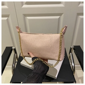Détail du sac bandoulière en paille tressée rose avec bandoulière chaîne dorée