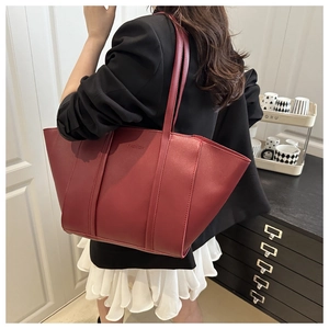 Detailed view of burgundy leather tote bag with Fashion embossed text and long straps